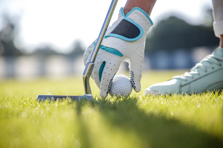 A golfer setting a ball on the tee