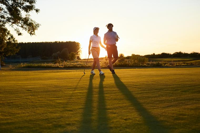 Two golfers walking the fairway at sunset
